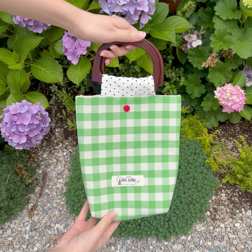 Green grid wooden handle bag in a garden