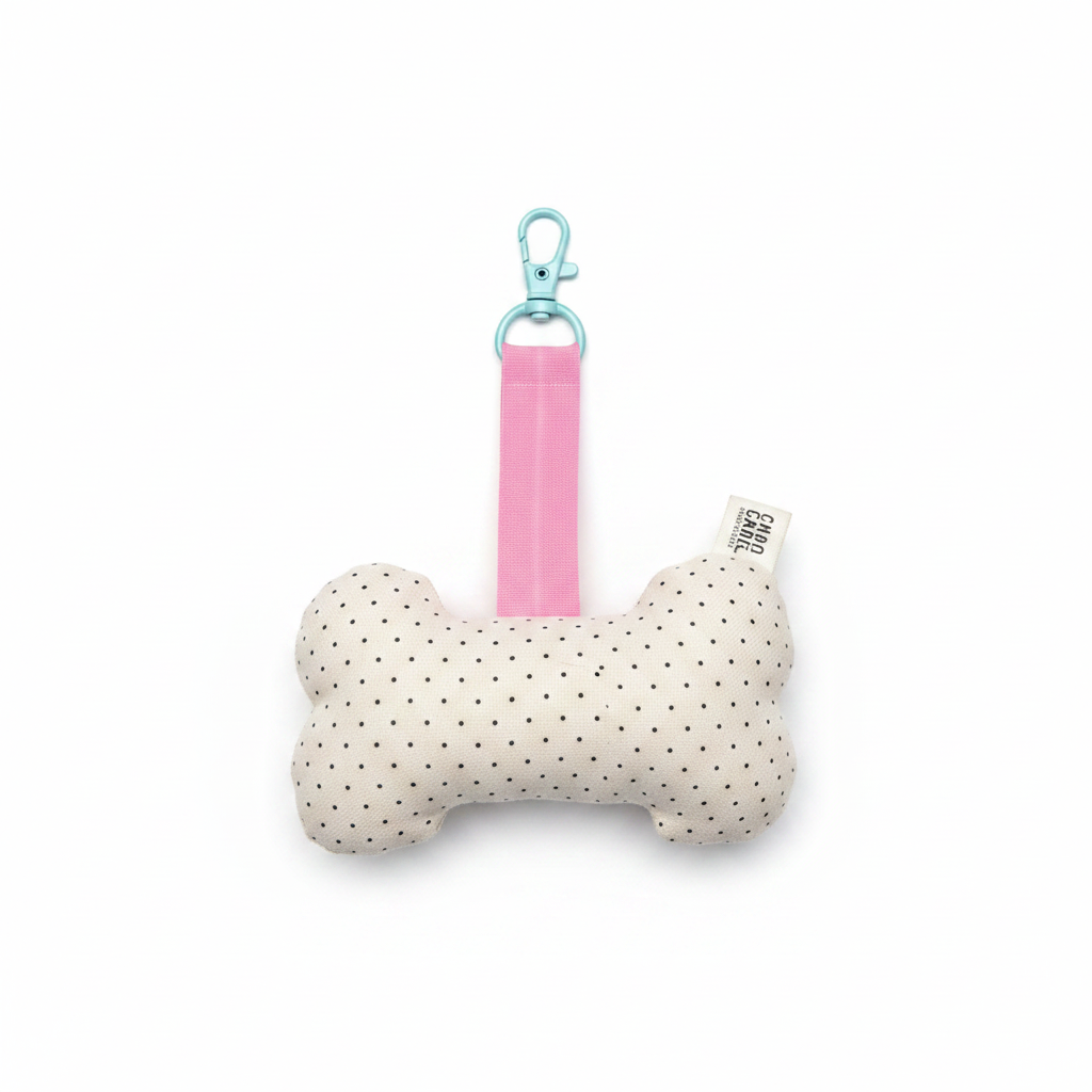 Handmade bone-shaped dog toy keychain, cream fabric with black polka dots, pink strap and teal clip