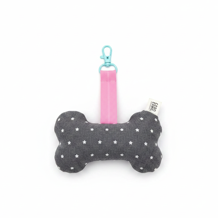 Handmade bone-shaped dog toy keychain, dark grey fabric with white stars, pink strap and teal clip