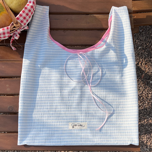 Blue Stripe Airy Tote Bag placed on a table with natural sunlight and shadows