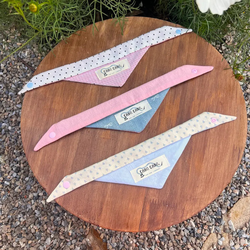 Kang Kang handmade dog triangle scarf set of 3, flat lay on wooden surface showing all three colorways