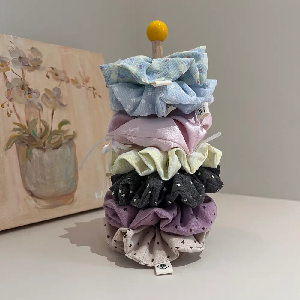The Scrunchie Family – handmade fabric hair scrunchies in multiple colors and patterns, flat lay