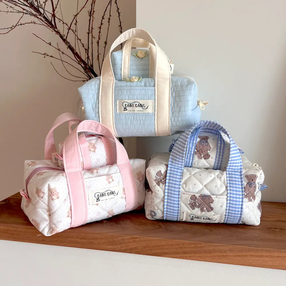 Kang Kang Handmade Together Bag in three colorways — Powder Blue, Bear Blush, and Bear Plaid — displayed together on a wooden shelf